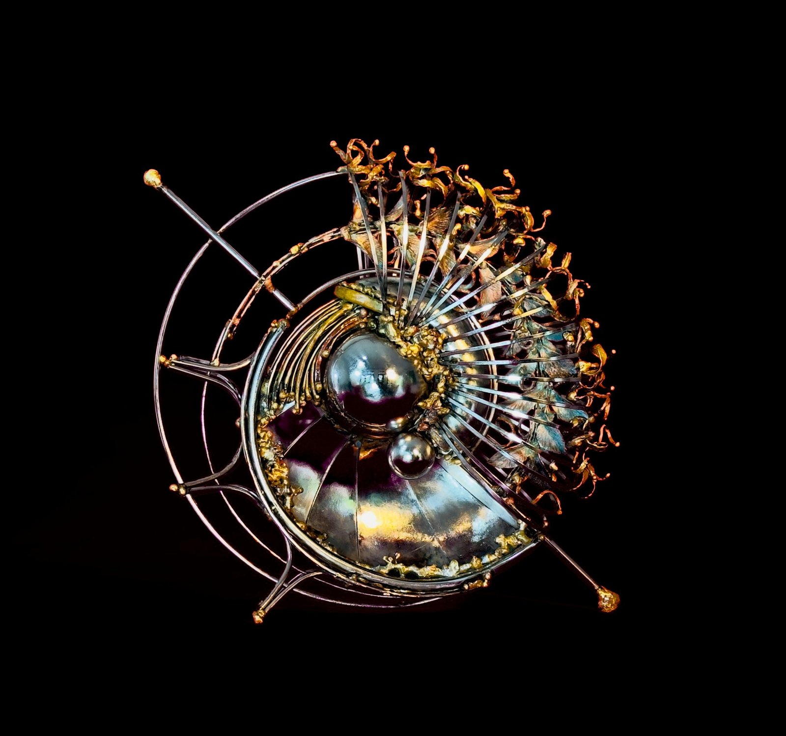 Metal sculpture of brass, copper and steel: a sphere inside rings with a crown of rays